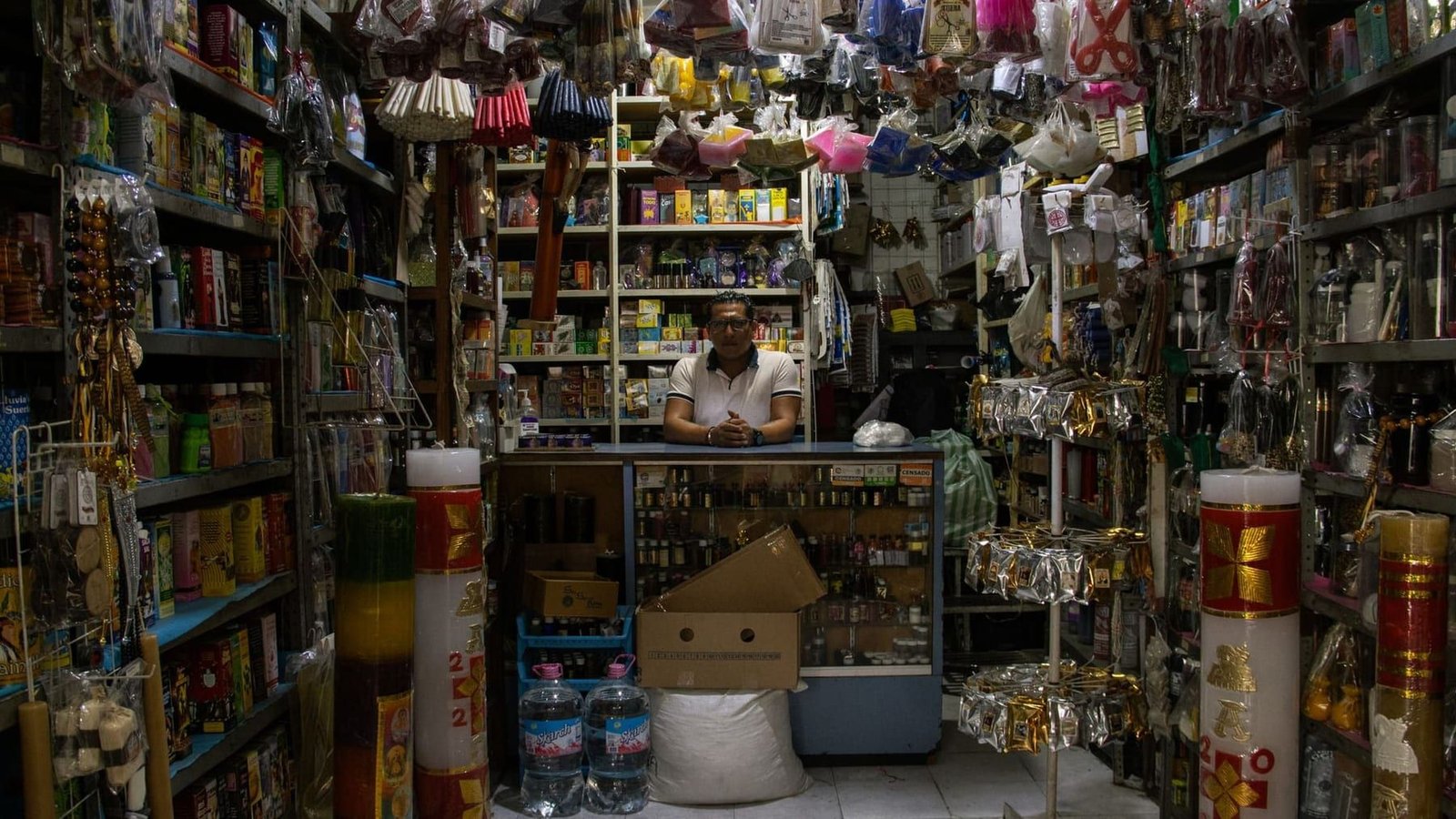 Interior of a densely stocked general store, goods filling shelves floor to ceiling along a narrow aisle.
